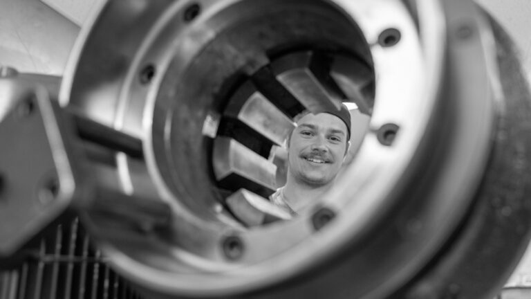 Smiling Corestock employee visible through circular opening in machinery